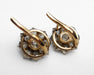 A pair of vintage gold and silver-toned earrings with clear gemstones, photographed on a white textured fabric background.
