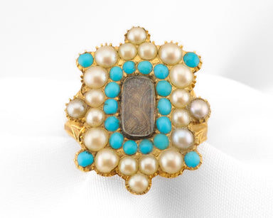 A vintage gold ring featuring a central rectangular brown stone surrounded by a double row of turquoise and white pearls in a floral cluster setting.